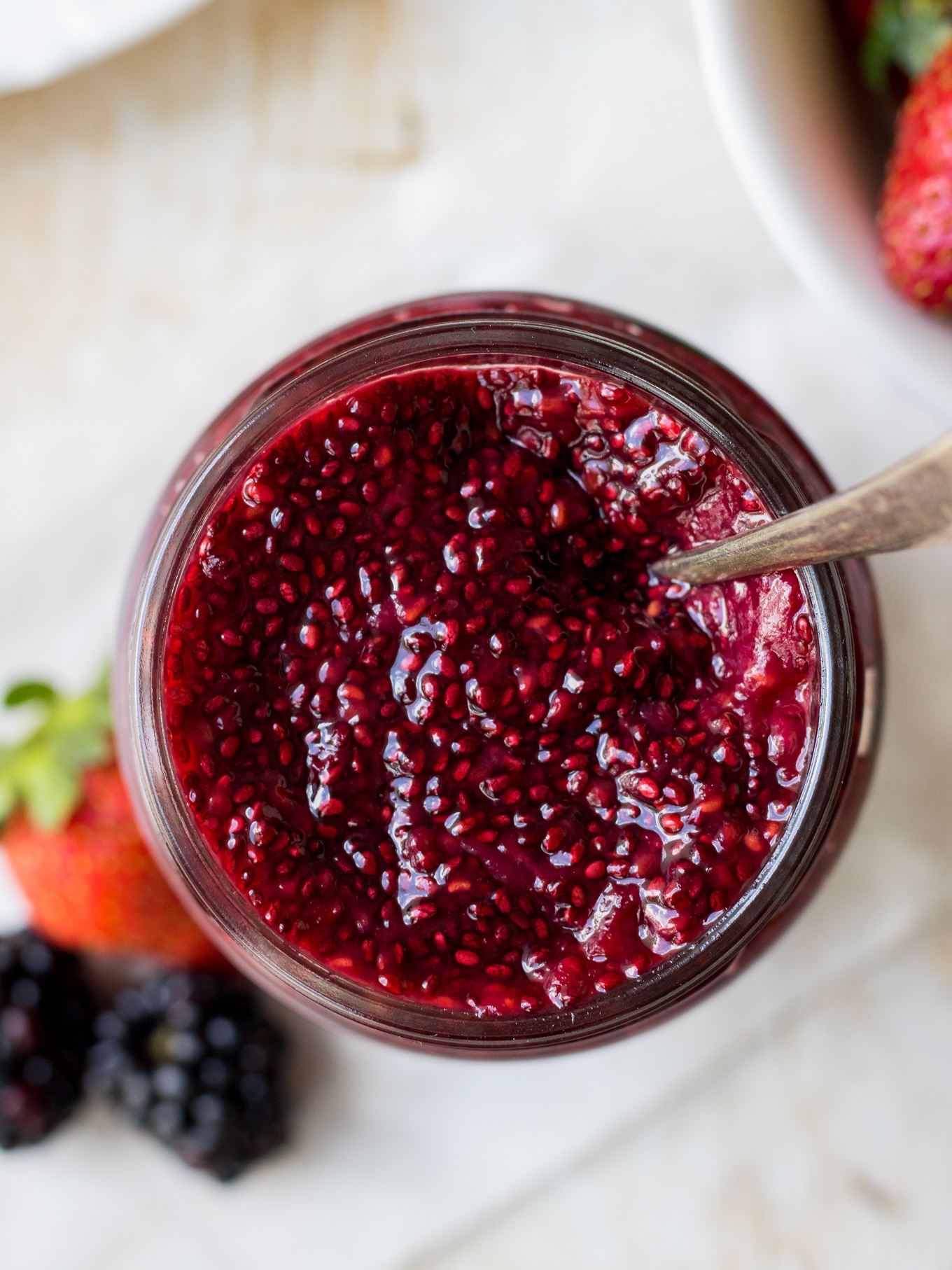 Image of chia jam jar from top down showing berry jam in glass jar with a few berries at base of jar.