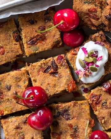 Nut Free Vegan Fruit Slice in baking tray topped with coconut yoghurt and fresh cherries!