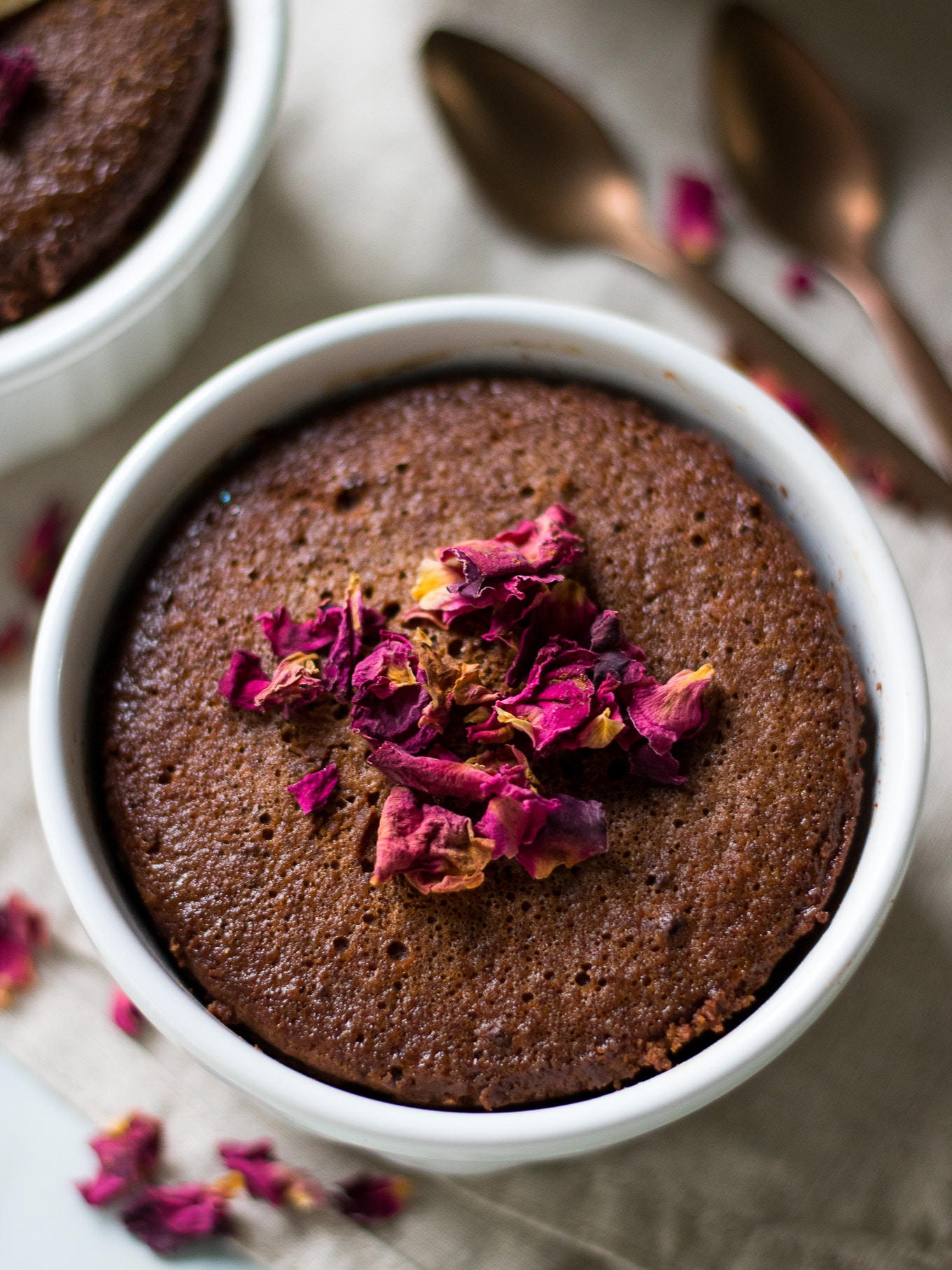 Single serve chocolate cake in white ramekins topped with pink rose petals