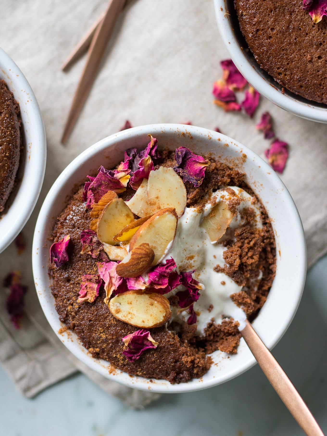 Chocolate cake single serve in a white ramekin with yoghurt and flaked almonds