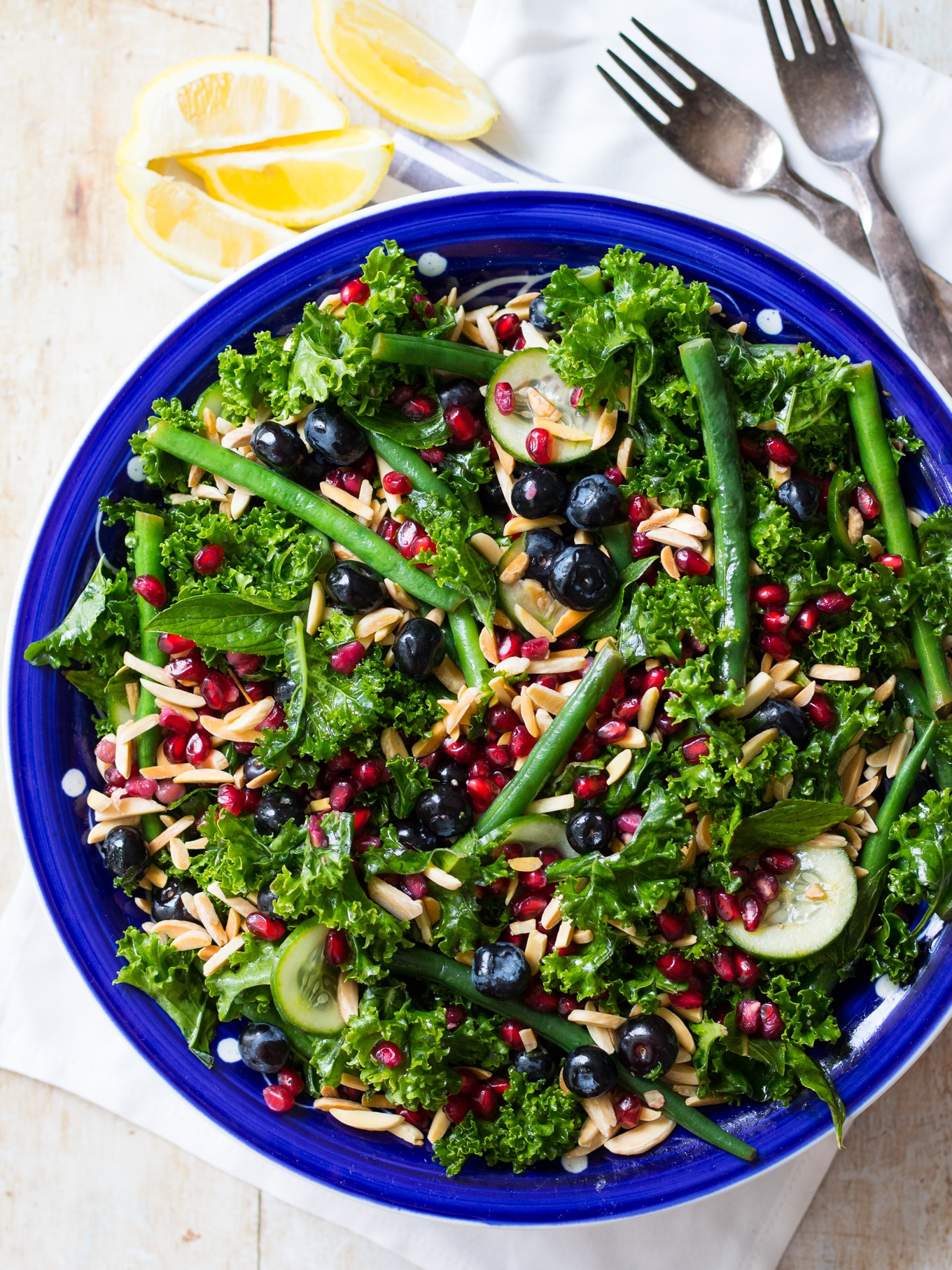 A summery blueberry kale salad filled with vibrant healthy greens, blueberries, pomegranate and crunchy toasted almonds. Perfect for sharing at a BBQ or any dinner party! Gluten free, dairy free, grain free and paleo. #kalesalad