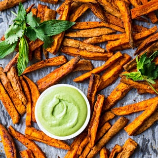 Cinnamon Paprika Sweet Potato Fries roasted on a baking tray, with dipping sauce and fresh mint.