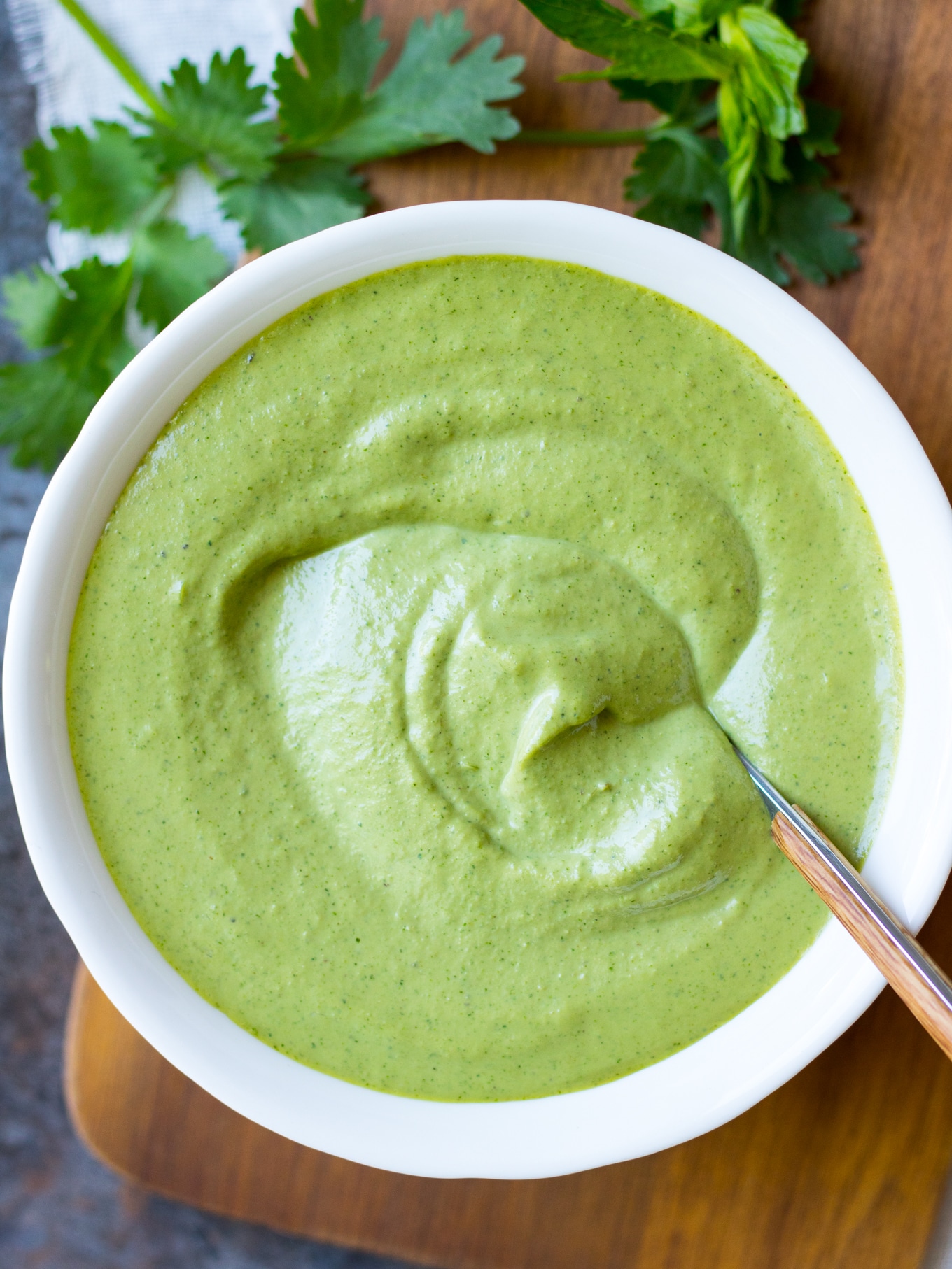 Cashew Tahini Herb Sauce close up, in a white serving bowl with a spoon.