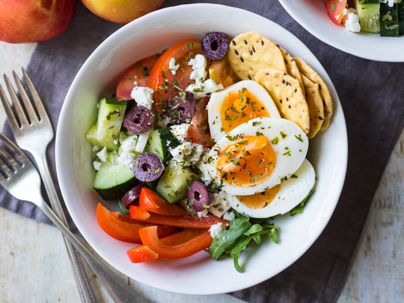 Meal prep breakfast bowls Greek style. Healthy breakfast salad pots featuring sliced boiled eggs with rocket, cucumber, tomatoes, capsicum, feta, olives, herbs and extra virgin olive oil.