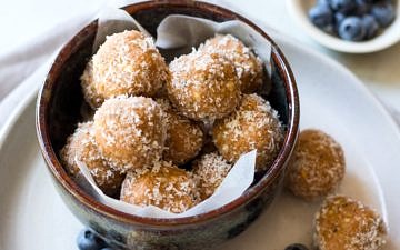 No food processor Paleo Protein Balls, all stacked in a bowl! Combining crunchy nut butter, coconut, hemp seeds, a little honey and your favourite protein powder.
