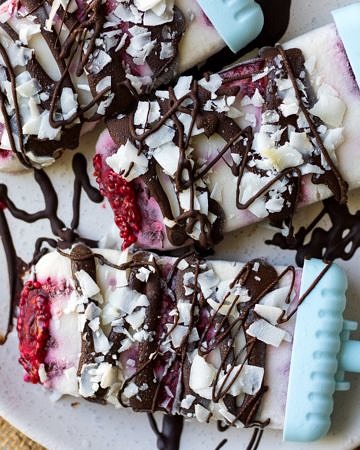 Vegan creamy coconut lamington popsicles drizzled in dark chocolate and sprinkled with coconut flakes.