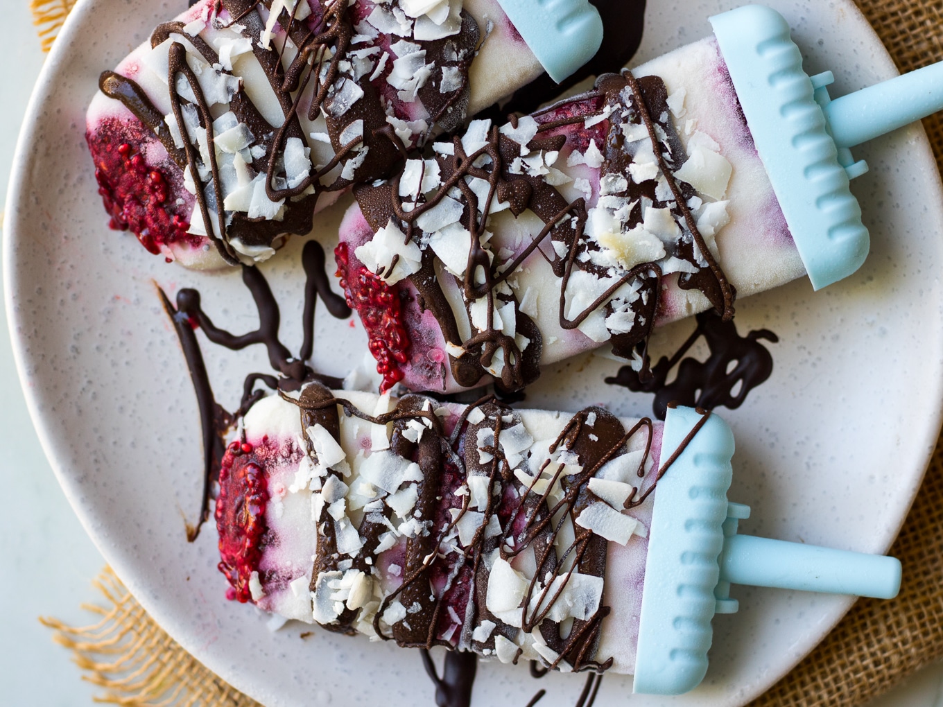 Vegan creamy coconut lamington popsicles drizzled in dark chocolate and sprinkled with coconut flakes.