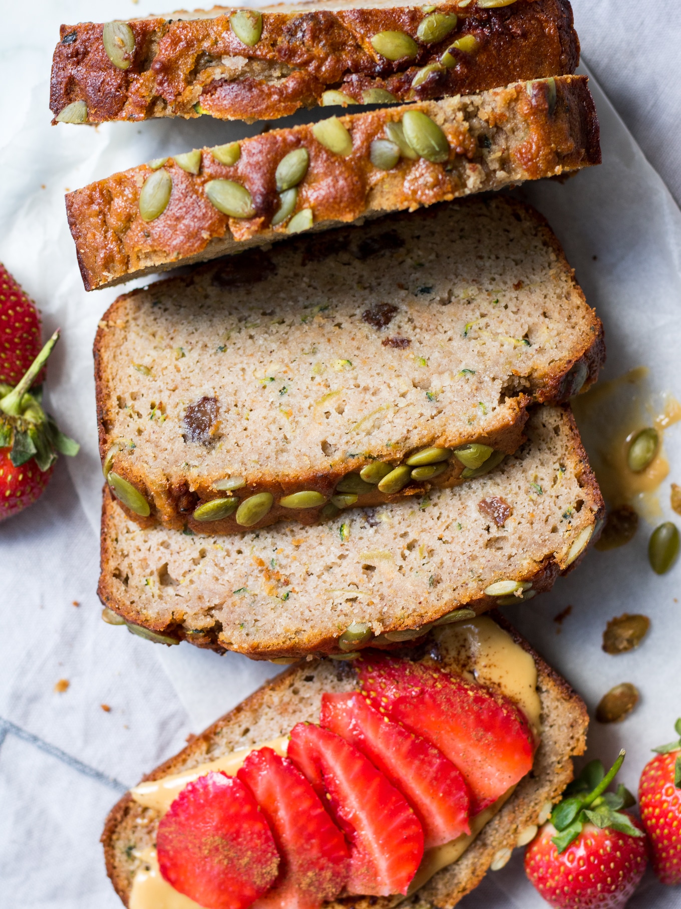 Slices of apple zucchini snack cake from top down, one flat topped with sliced strawberries