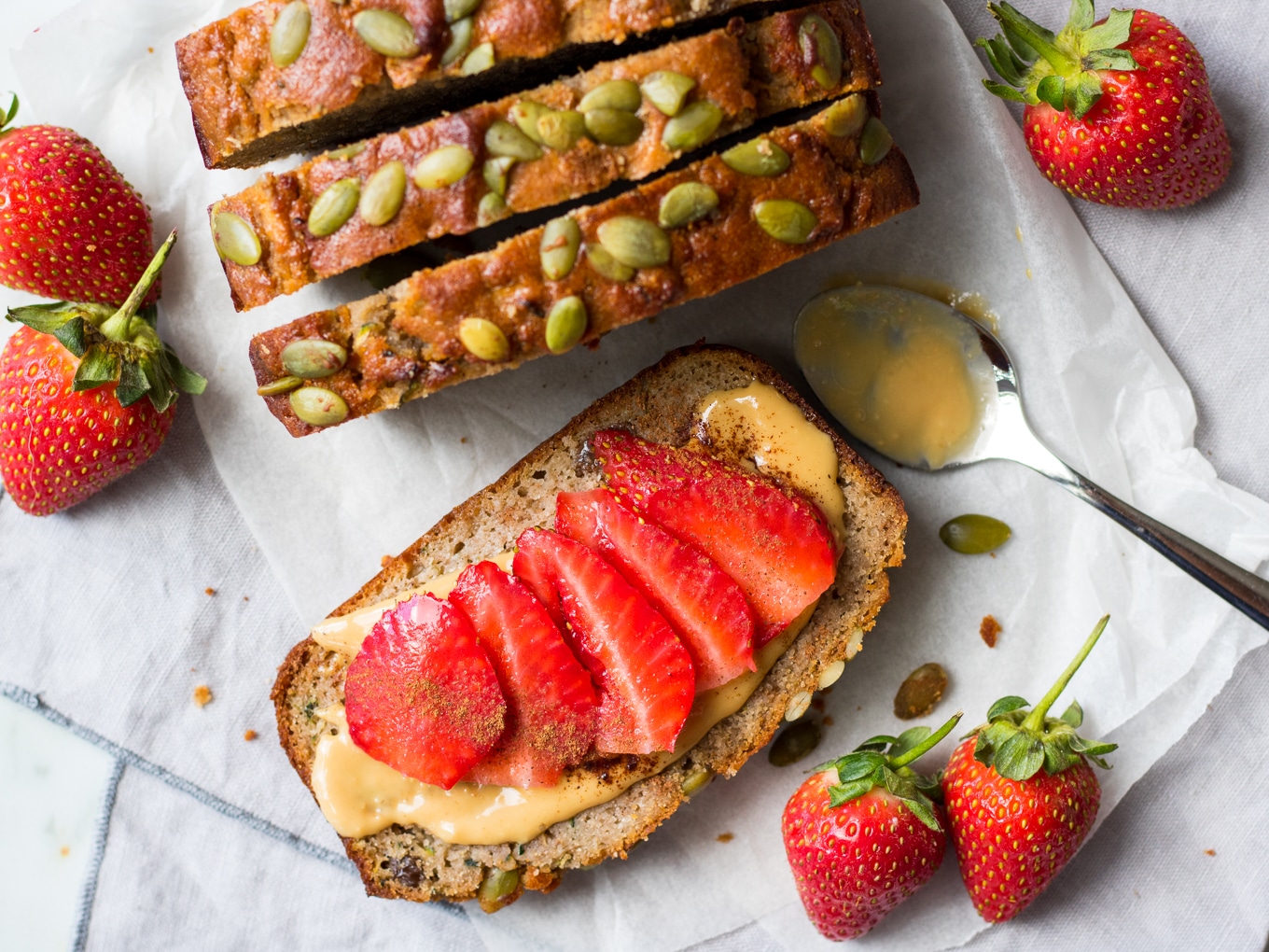 Slices of apple zucchini snack cake from top down, one flat topped with sliced strawberries