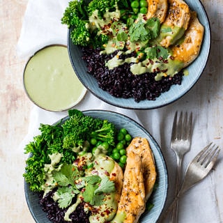 Chicken black rice bowls; two blue bowls filled with black rice, chicken and broccolini, side of green herb sauce, on a light table