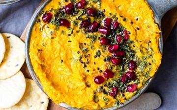 Roasted carrot tahini tip in a small grey dish on a wooden chopping board.