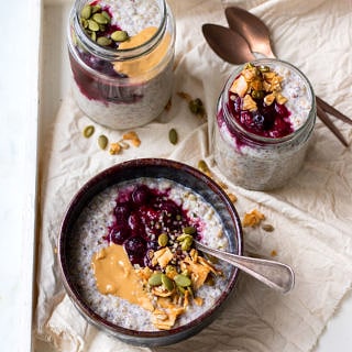 One bowl and two jars of buckwheat bircher, topped with berries and granola