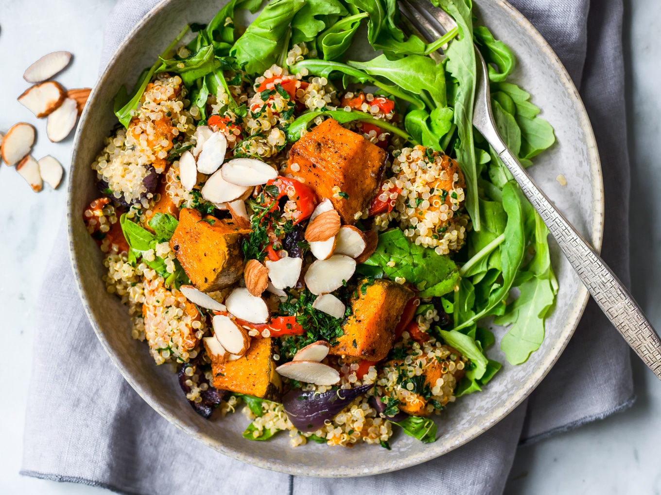 pumpkin quinoa salad in grey ceramic shallow bowl, fork nestled in side