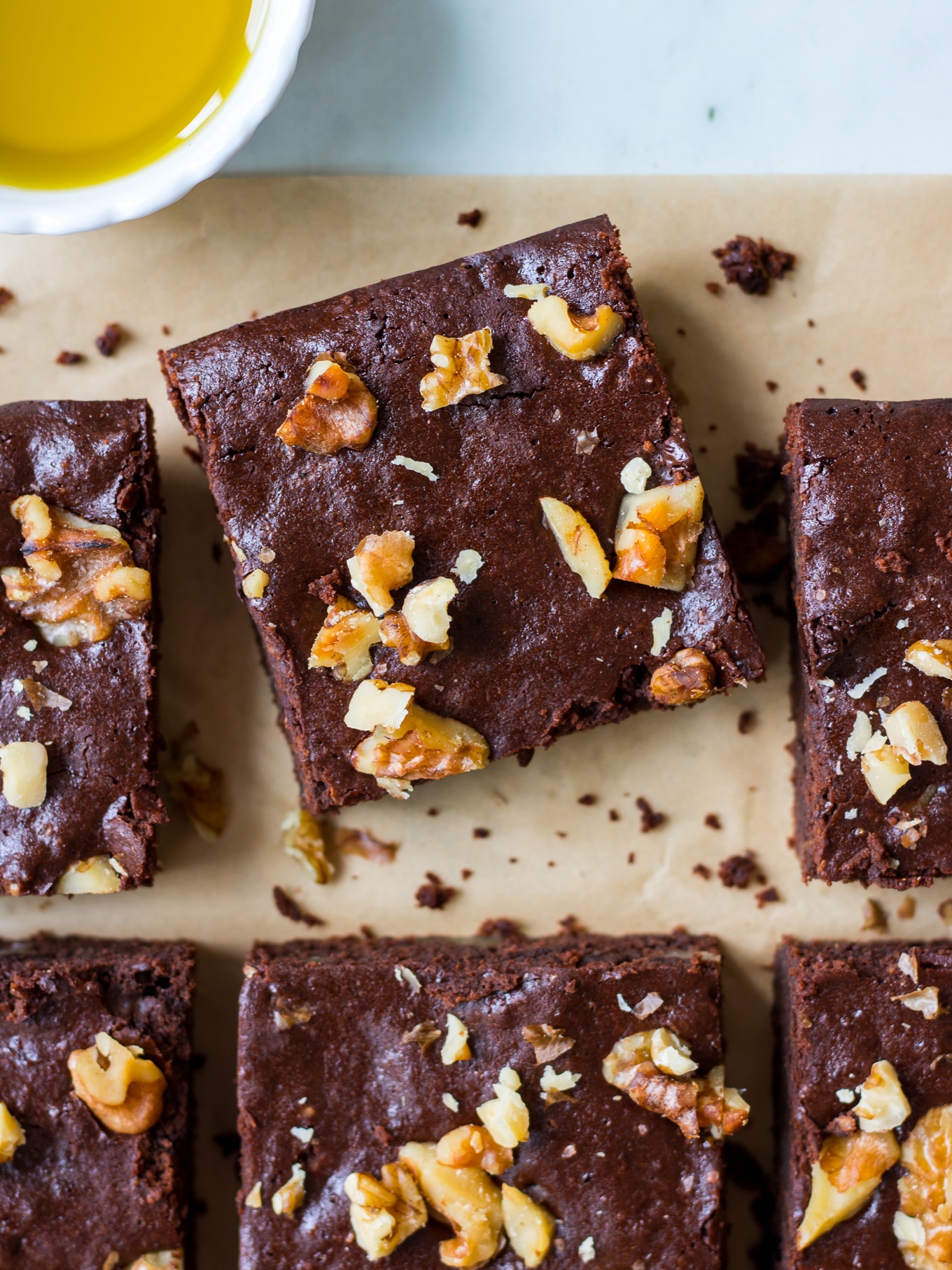 Olive oil chocolate brownies close up, one brownie in focus, on an angle, topped with walnuts