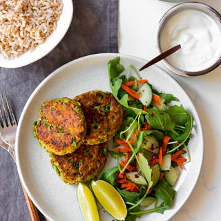 thai salmon cakes on white plate with side salad and lime