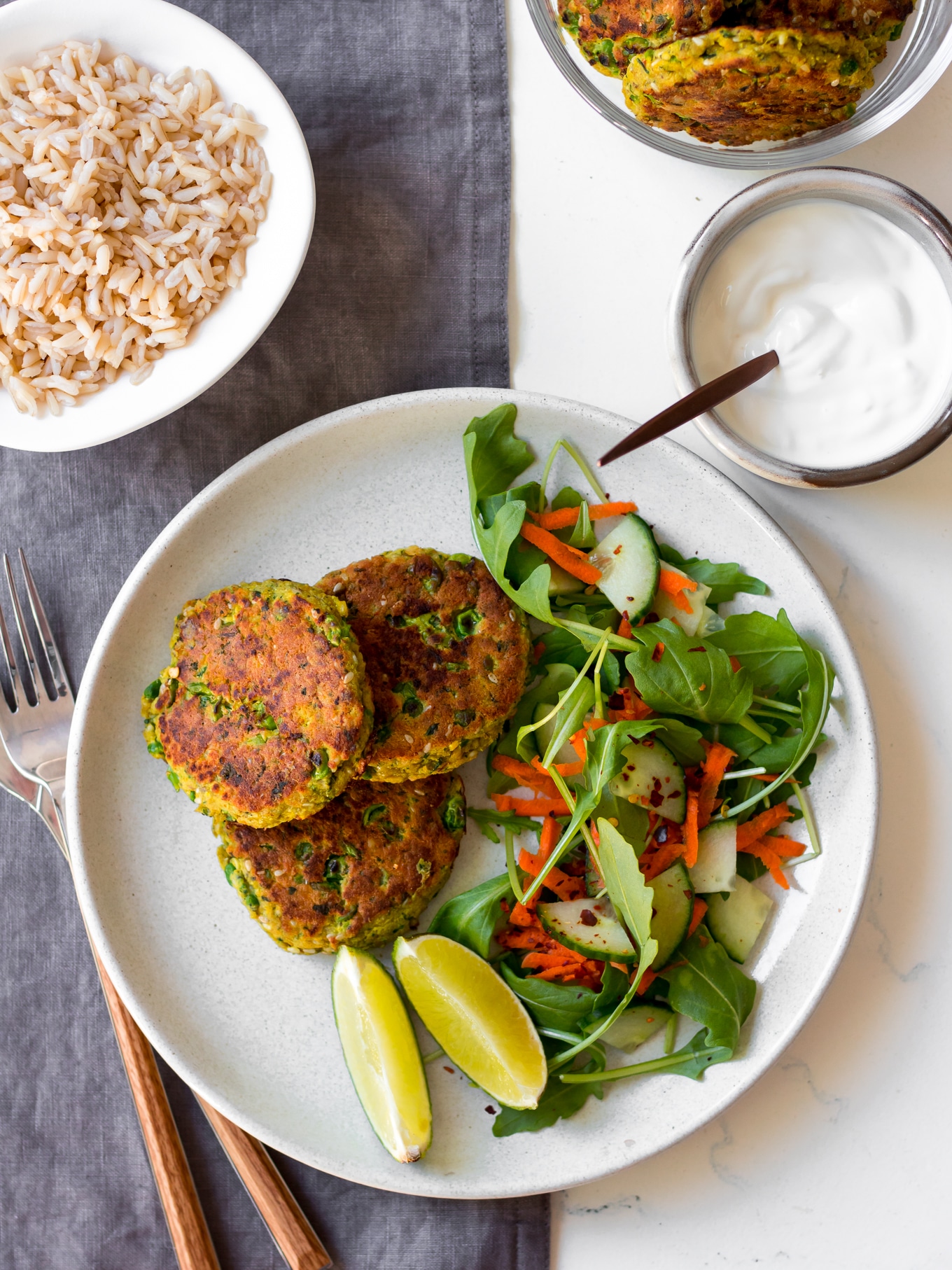 thai salmon cakes on white plate with side salad and lime