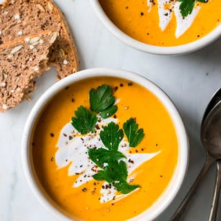 coconut ginger pumpkin soup bowl garnished with coconut cream and herbs