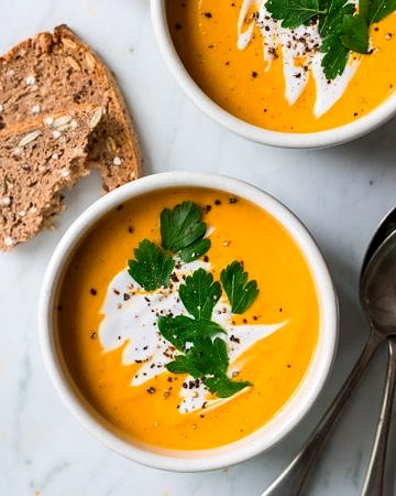 coconut ginger pumpkin soup bowl garnished with coconut cream and herbs