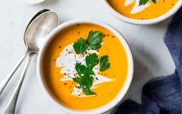 coconut ginger pumpkin soup bowl garnished with coconut cream and herbs