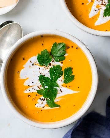 coconut ginger pumpkin soup bowl garnished with coconut cream and herbs