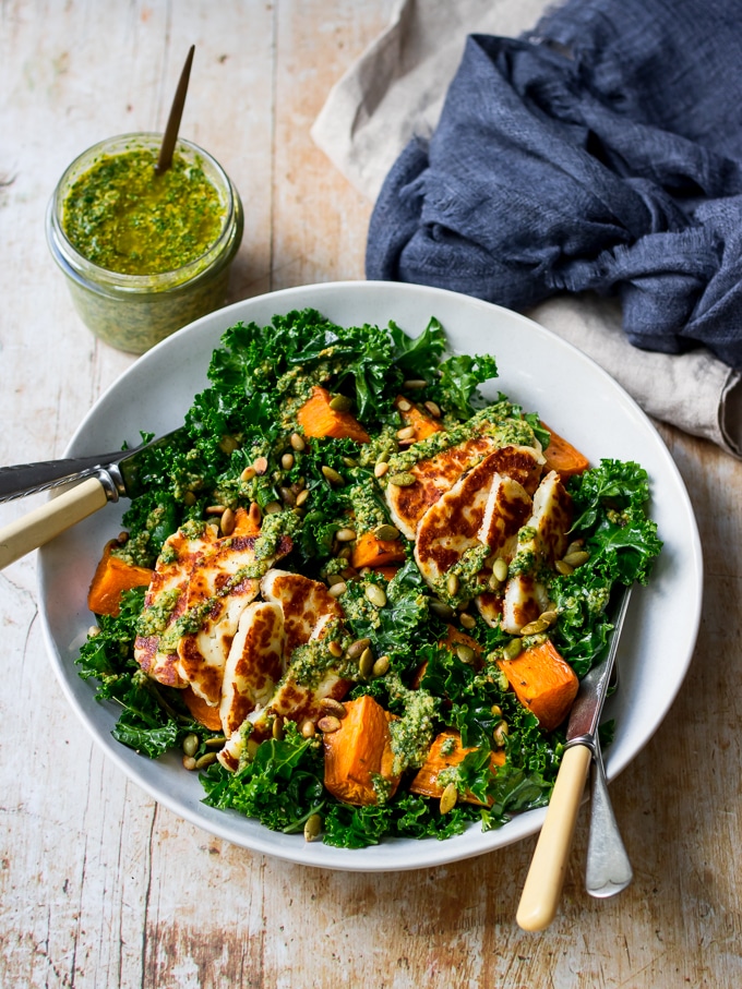 Halloumi kale salad in grey ceramic bowl, pesto sauce, wooden table top