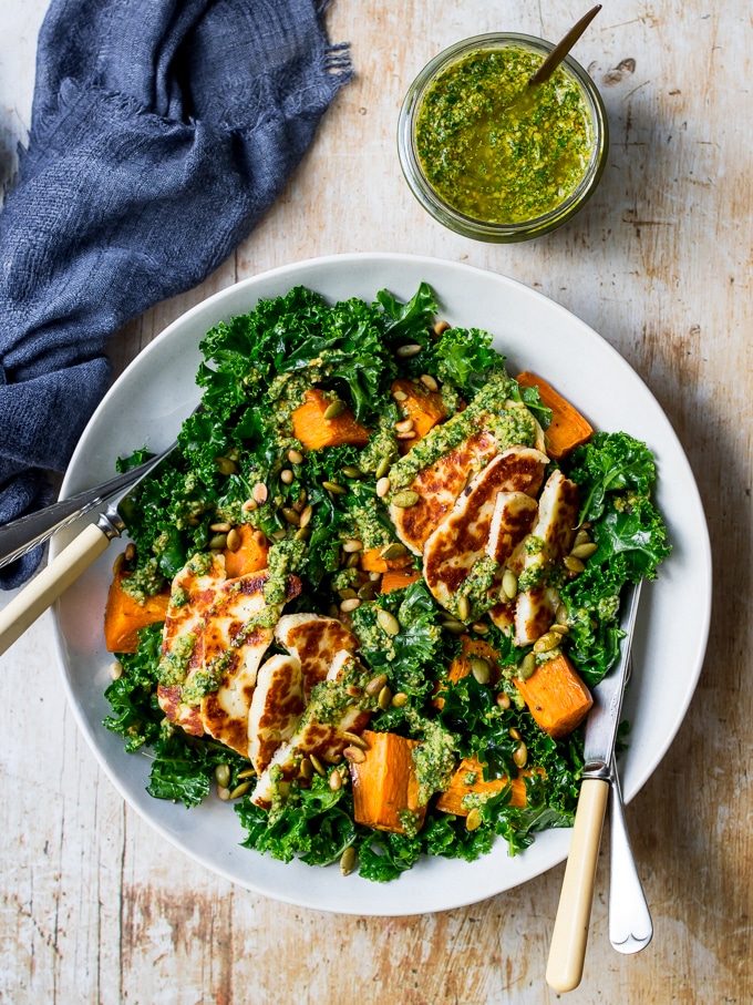 Halloumi kale salad in grey ceramic bowl, pesto sauce, wooden table top