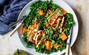 Halloumi kale salad in grey ceramic bowl, pesto sauce, wooden table top