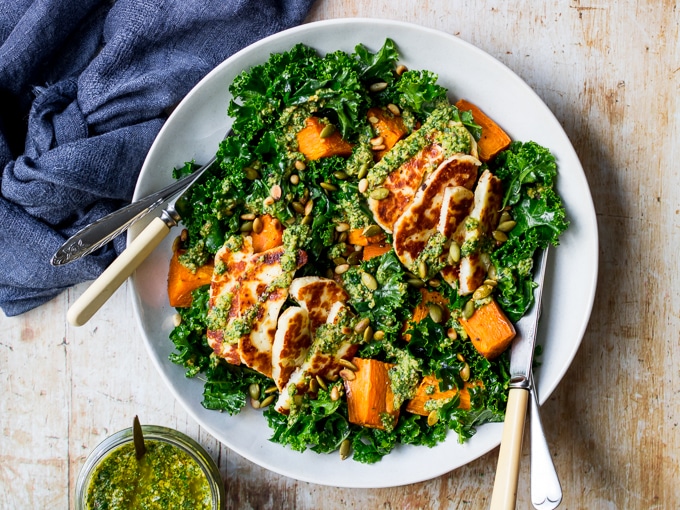 Halloumi kale salad in grey ceramic bowl, pesto sauce, wooden table top