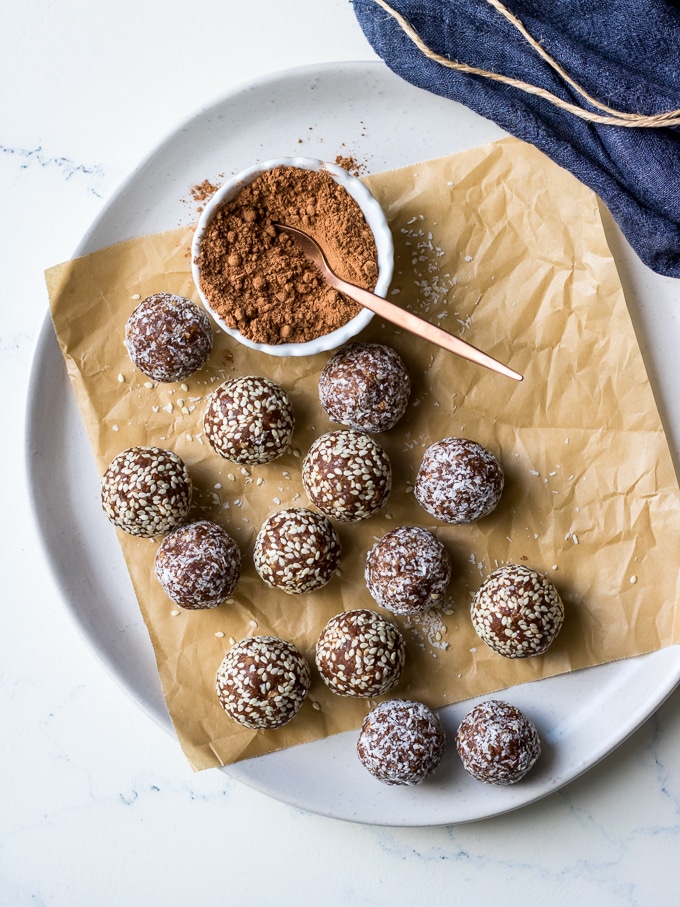 kakadu plum and ginger energy balls on white plate with cacao powder in dish