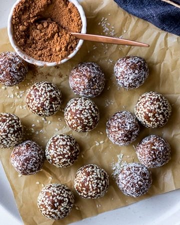 kakadu plum and ginger energy balls on white plate with cacao powder in dish