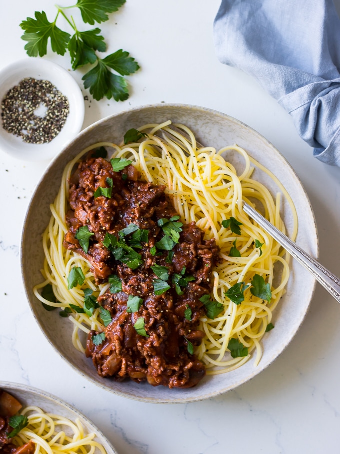 Red wine bolognese with mushrooms, ceramic bowl, spaghetti, parsley garnish