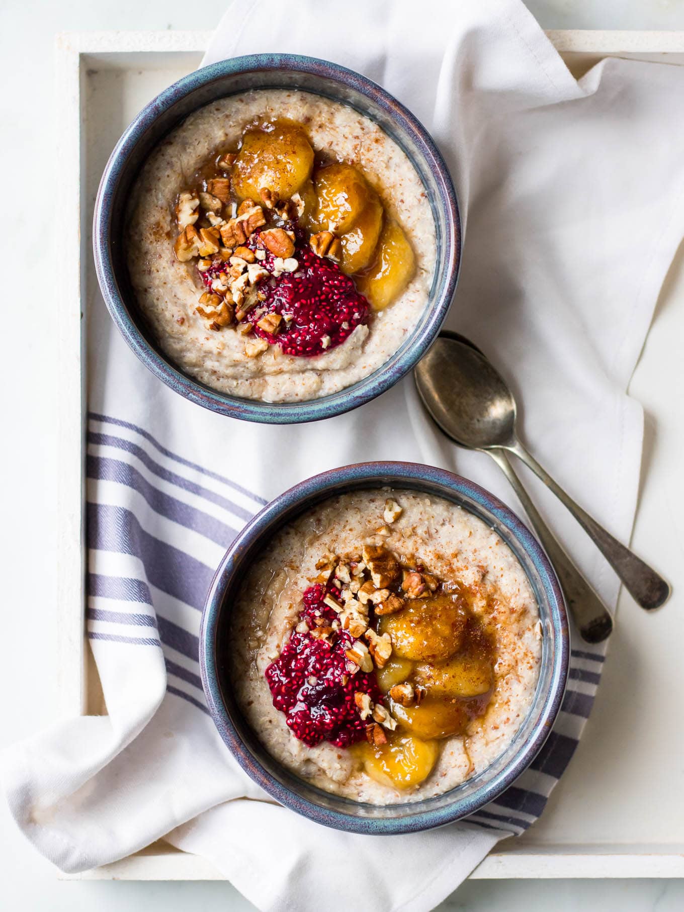 creamy quinoa porridge in blue ceramic bowls with berries and banana