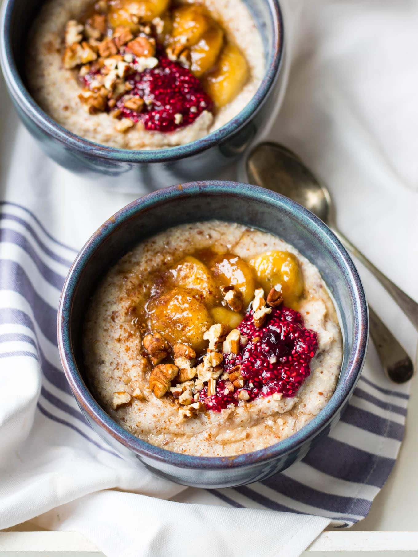 creamy quinoa porridge in blue ceramic bowls with berries and banana
