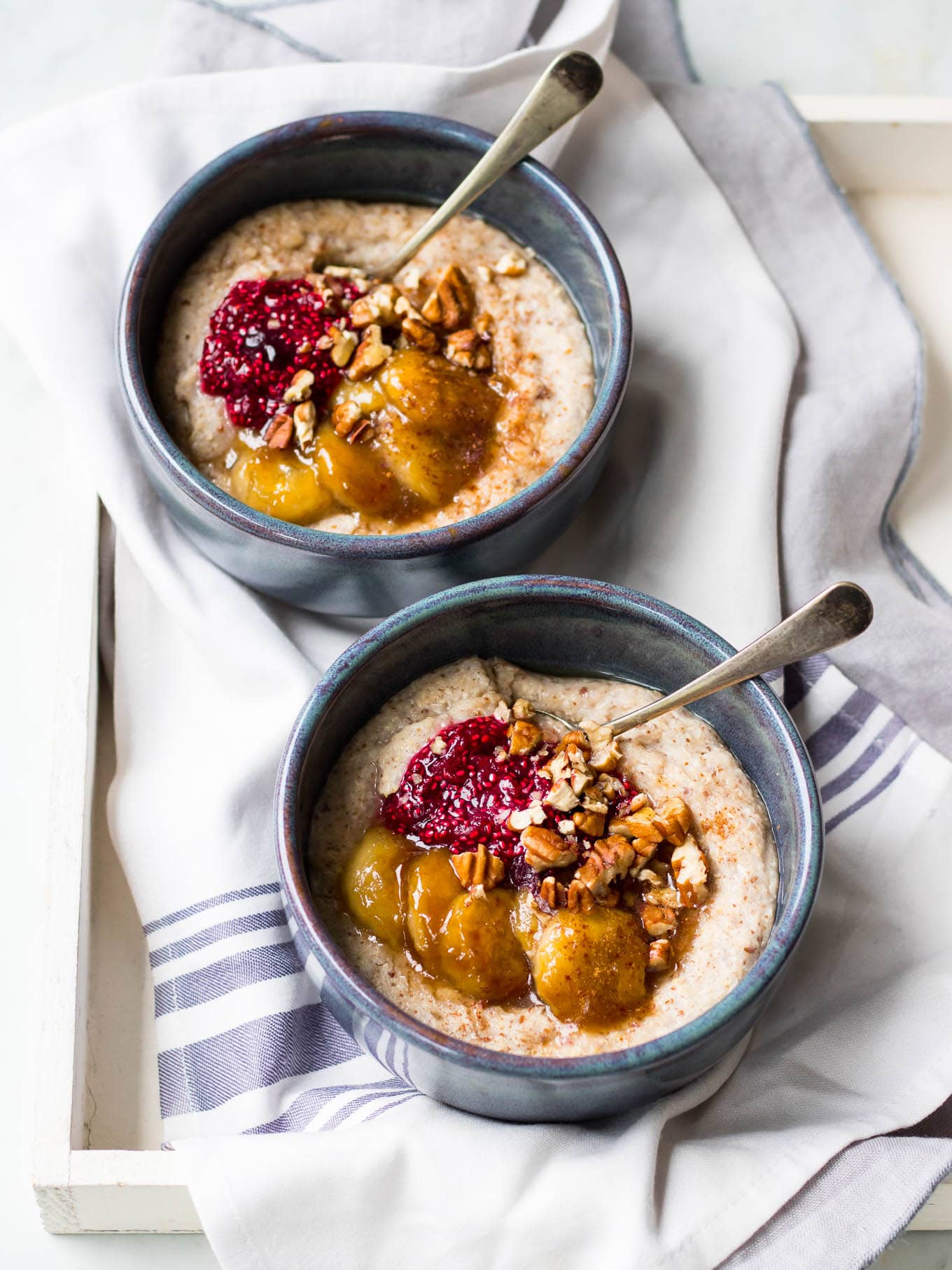 creamy quinoa porridge in blue ceramic bowls with berries and banana