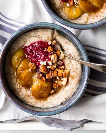 creamy quinoa porridge in blue ceramic bowls with berries and banana