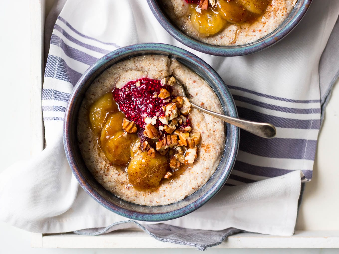 creamy quinoa porridge in blue ceramic bowls with berries and banana