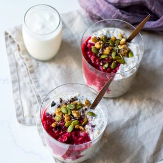 raspberry kefir overnight oats with glasses, topped with nuts, seeds, cacao nibs