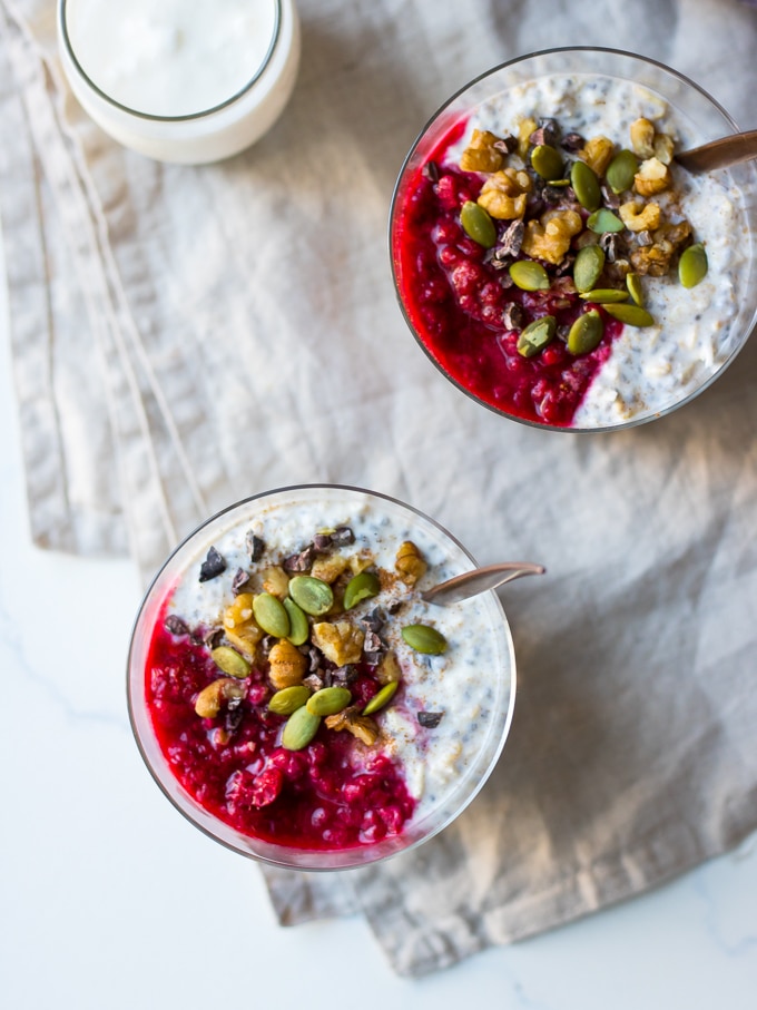 raspberry kefir overnight oats top view, topped with nuts, seeds, cacao nibs