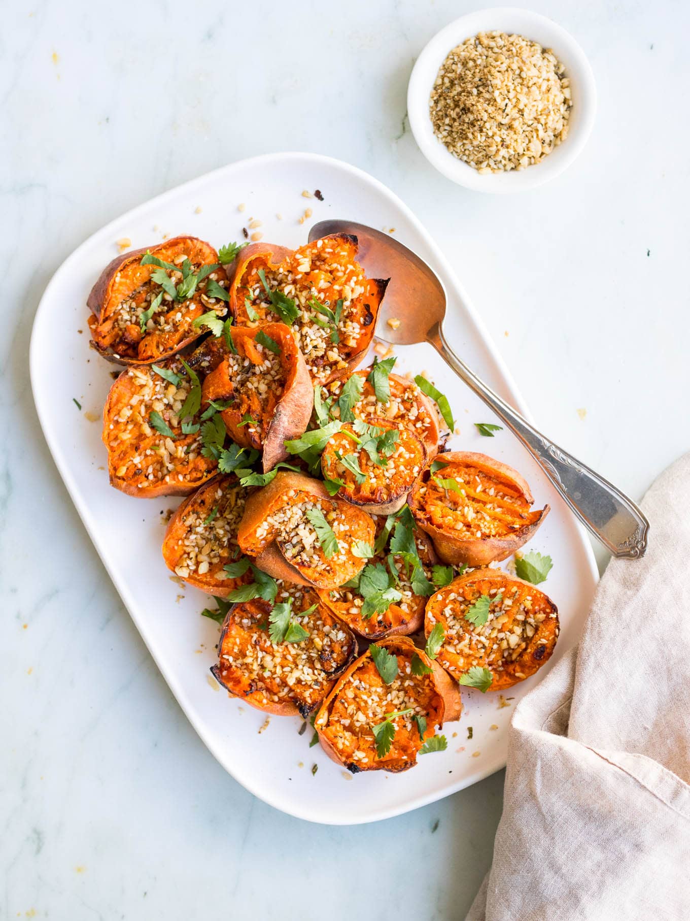 smashed sweet potatoes with dukkah on white serving platter
