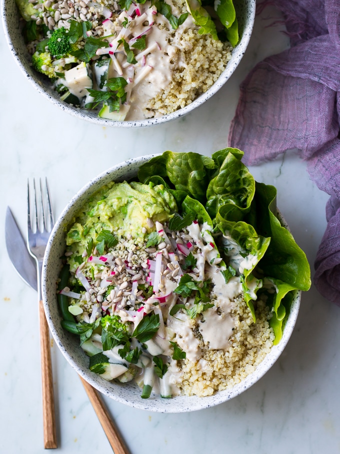 vegan protein buddha bowls with green vegetables, avocado smash, quinoa in white speckled bowls