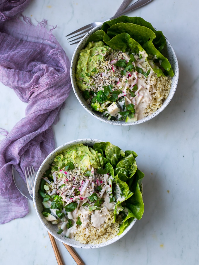 vegan protein buddha bowls with green vegetables, avocado smash, quinoa in white speckled bowls