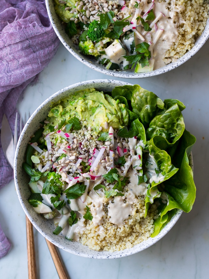 vegan protein buddha bowls with green vegetables, avocado smash, quinoa in white speckled bowls