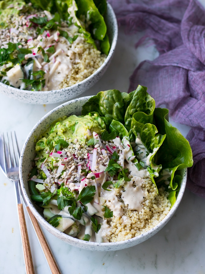vegan protein buddha bowls with green vegetables, avocado smash, quinoa in white speckled bowls