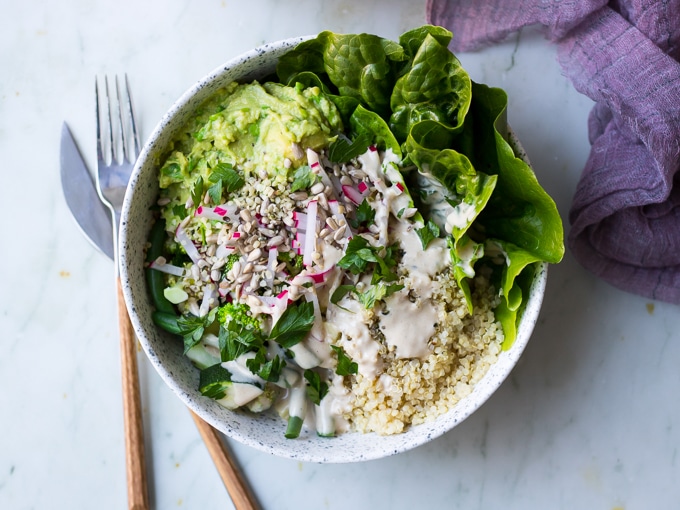 vegan protein buddha bowls with green vegetables, avocado smash, quinoa in white speckled bowls