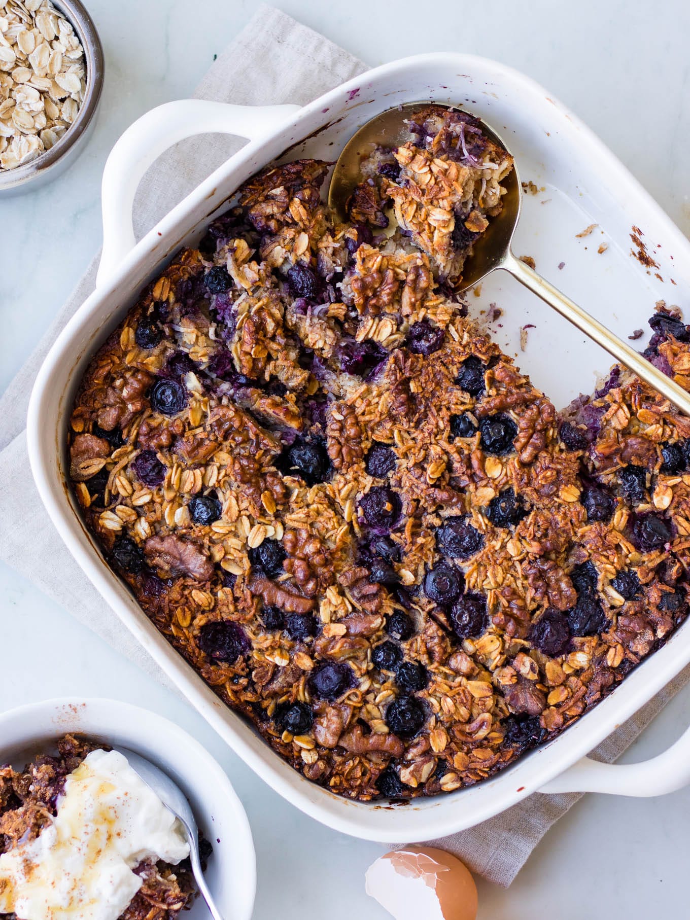 coconut blueberry baked oats in white baking dish, plus serving bowl