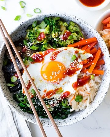vegetarian bibimbap bowls in white ceramic bowl with pickles