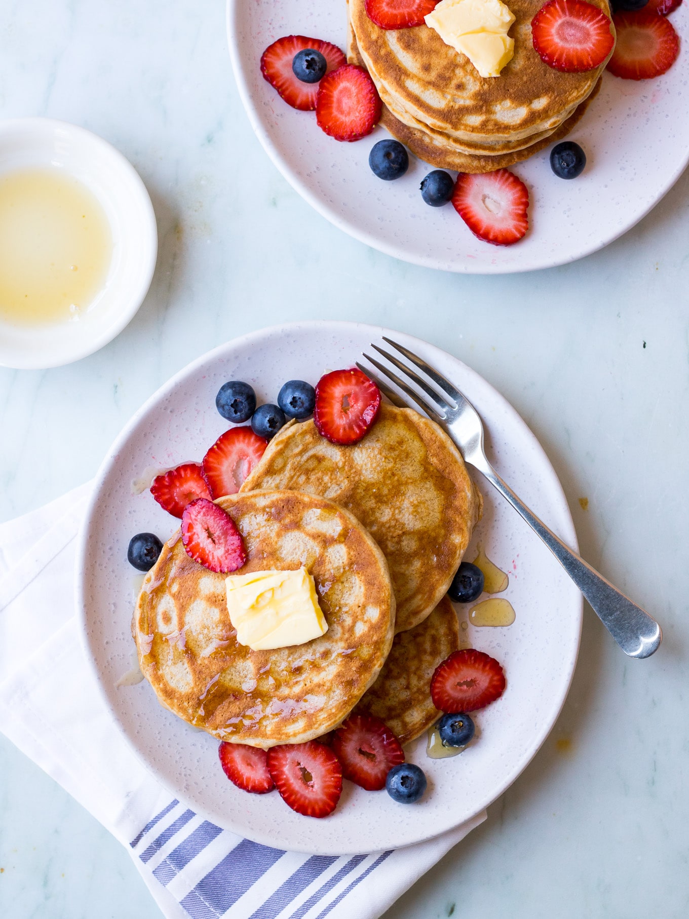 gluten free buckwheat pancakes on a white ceramic plate with fresh berries and maple syrup