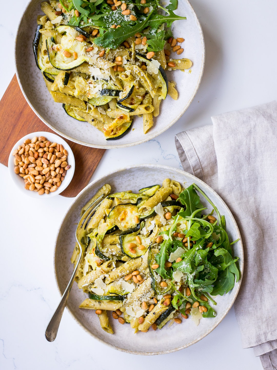 Pesto Pulse Pasta with Roasted Zucchini served in a grey ceramic bowl, with pine nuts