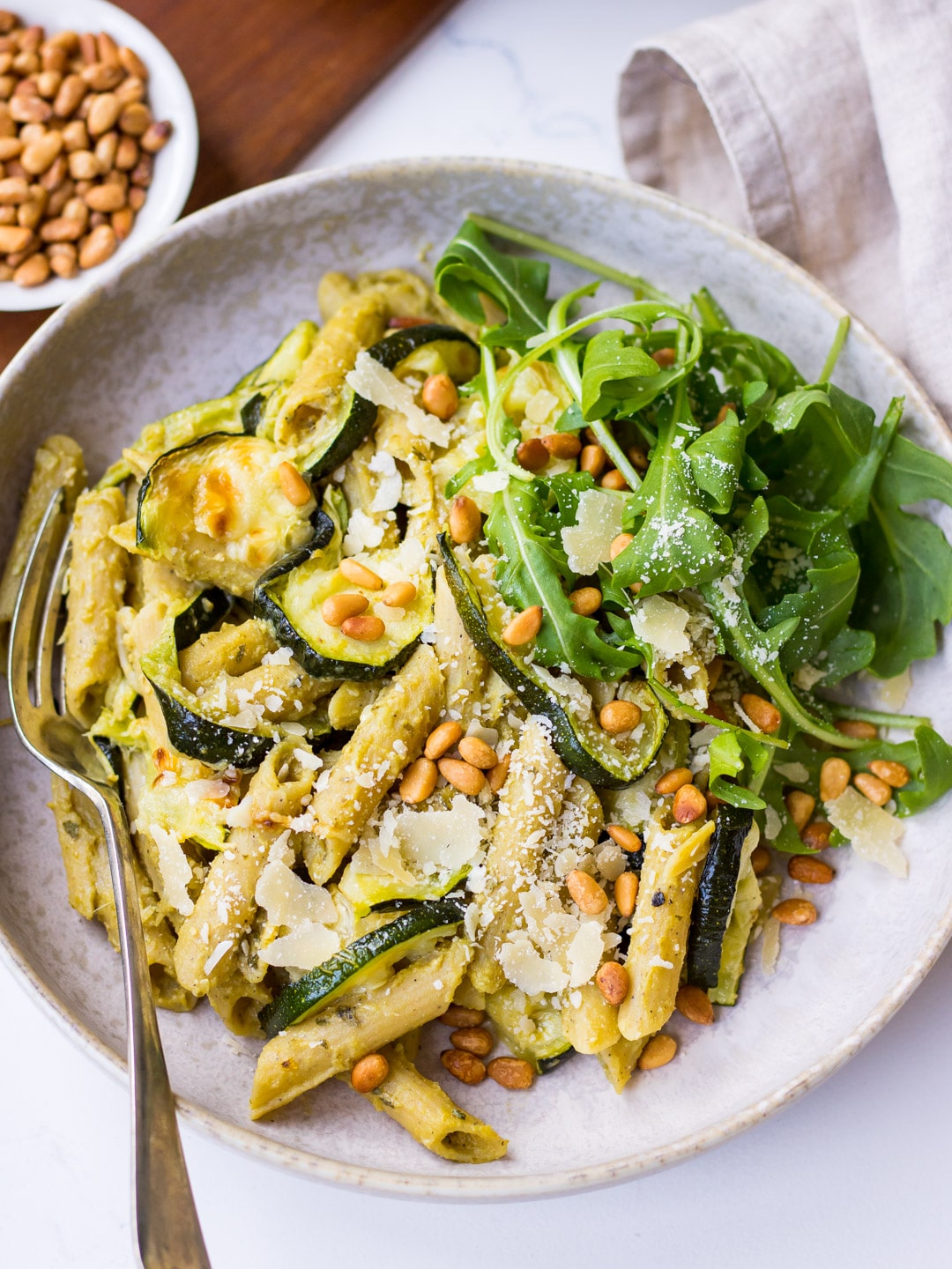 Pesto Pulse Pasta with Roasted Zucchini served in a grey ceramic bowl, with pine nuts