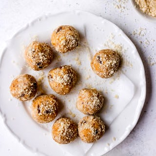 No bake Lactation Bites arranged on a white plate, scattered with almond meal (by Nourish Every Day)